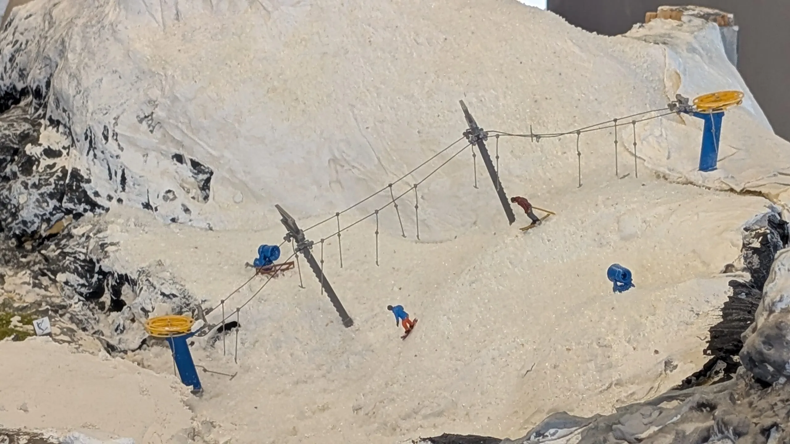 Skifahrer und Snowboarder gleiten den Hang hinunter, während die Schneekanonen leise surren und frischen Pulverschnee über den Berg verteilen